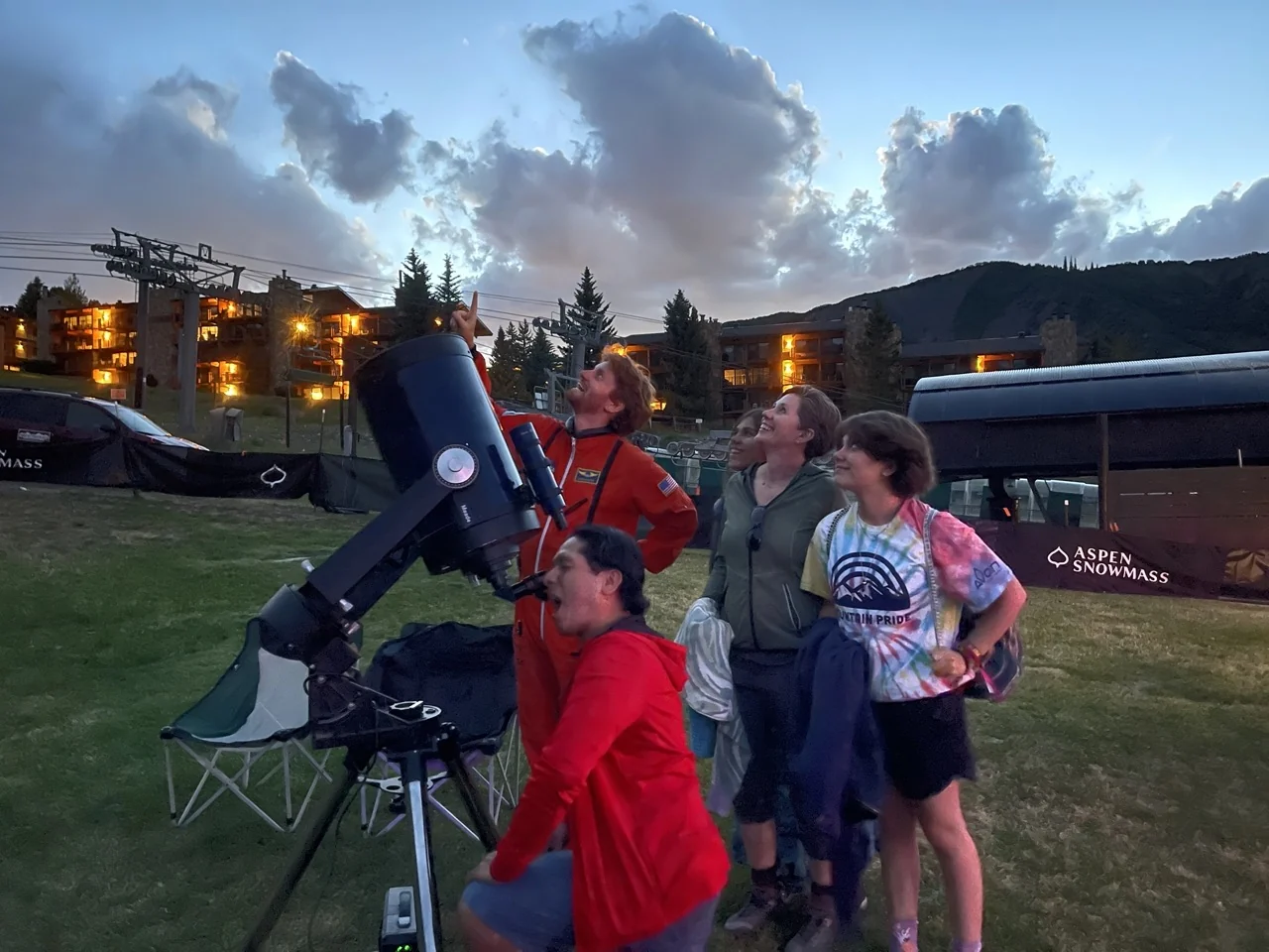 A family taking turns at a large telescope at dusk during an AstroTours program